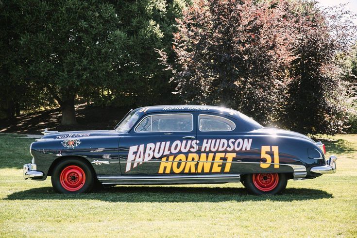 an old fashioned car is parked in the grass