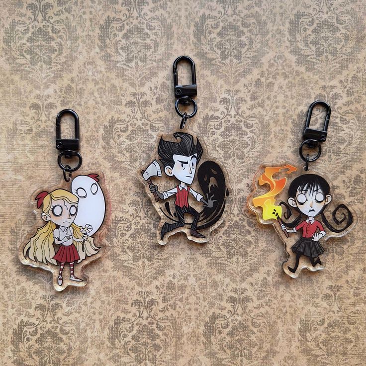 three keychains with cartoon characters on them sitting next to each other in front of a wall