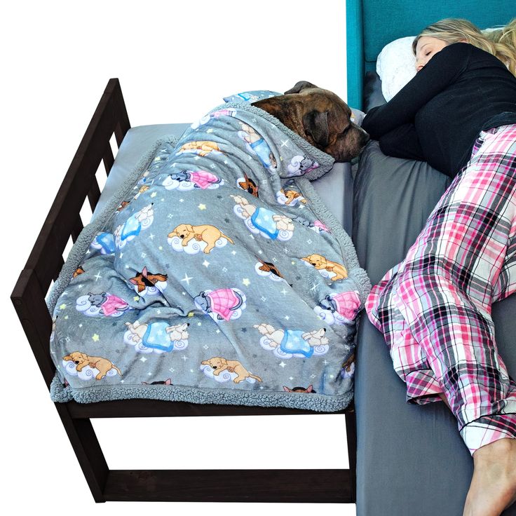 a woman laying in bed with her dog sleeping next to her on the edge of the bed