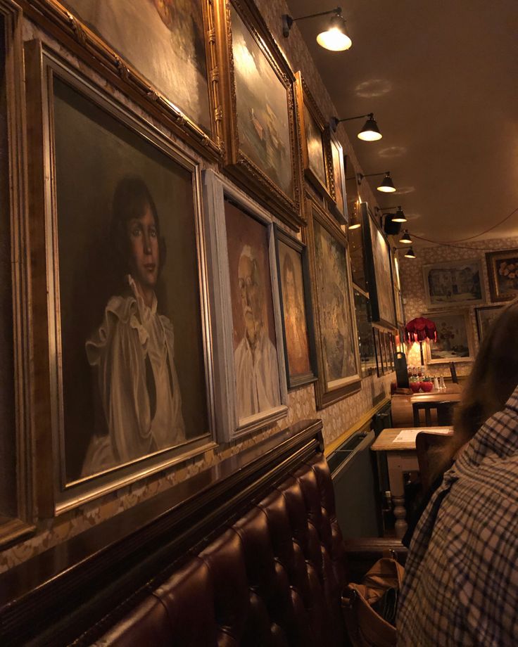 a man sitting at a table in front of paintings