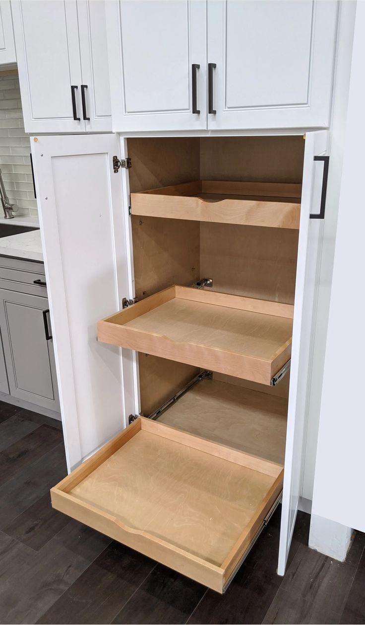 an open cabinet in a kitchen with white cabinets