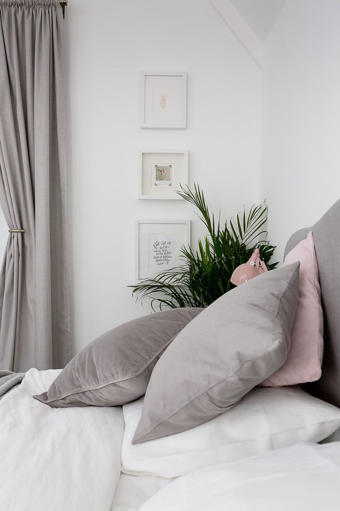 there is a bed with two pillows on it and a plant next to the pillow