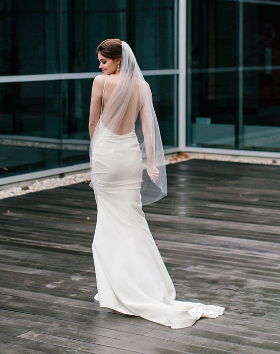 a woman in a wedding dress is standing on a wooden floor with her back to the camera