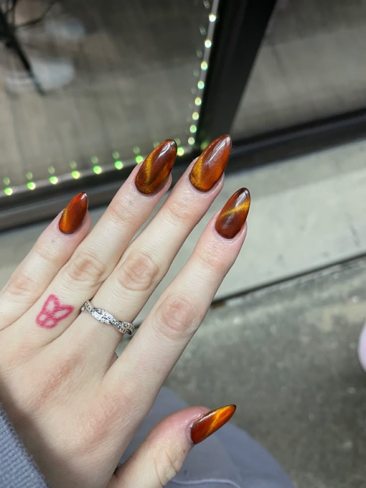 Almond Style Nails Fall, Cateye Fall Nails 2024, Almond Shape Thanksgiving Nails, Dark Orange Cat Eye Nails, Cat Eye Nails Almond Shape, Amber Colored Nails, Thanksgiving Cat Eye Nails, Autumn Cat Eye Nails, Orange Cateye Nails