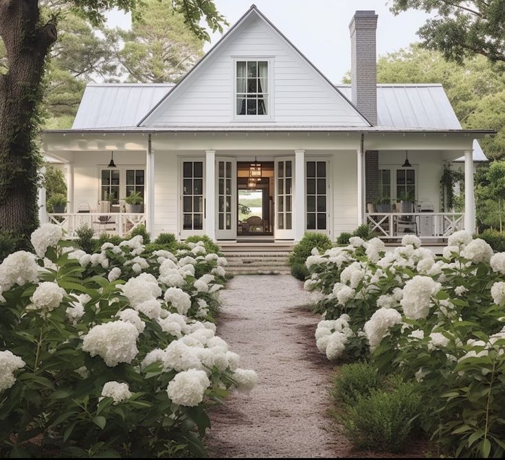 a white house surrounded by flowers and trees