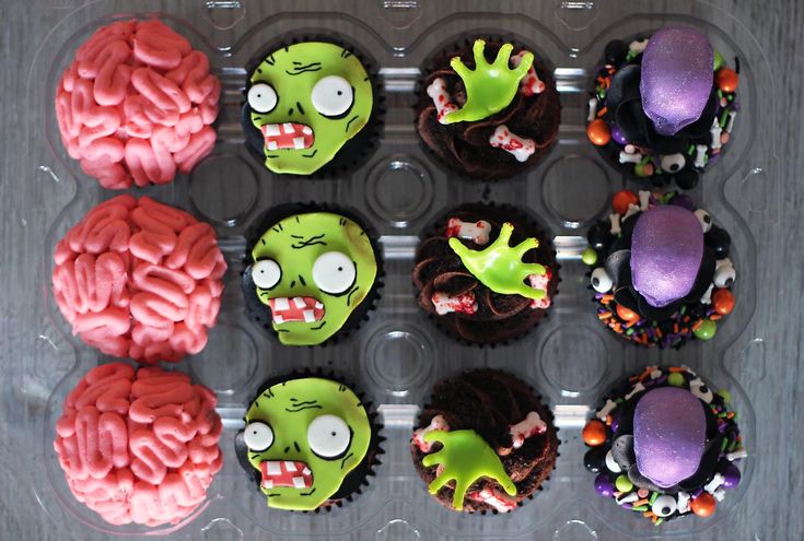 cupcakes decorated to look like zombies with brain and head decorations on each one