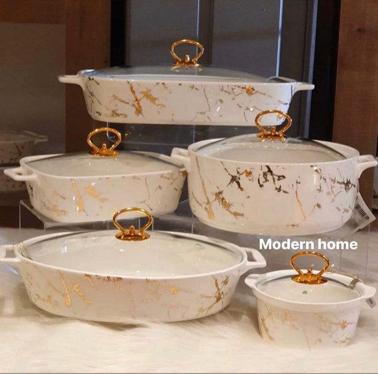 marbled white dishes with gold rings on the handles and rims sitting on a table