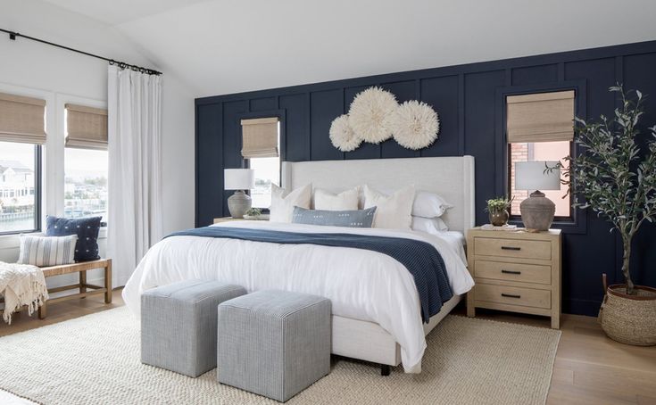 a bedroom with blue walls and white bedding, two stools on either side of the bed