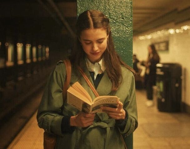 a woman standing in a subway station reading a book