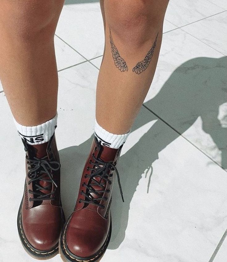 the legs and ankles of a person wearing red boots with tattoos on them, standing in front of a white tile floor