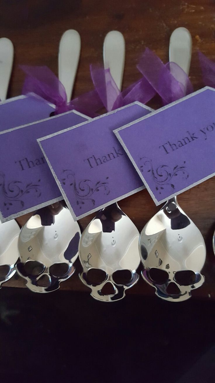 spoons with thank you notes on them sitting next to each other in front of purple ribbons