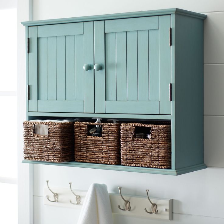 a blue cabinet with two baskets on it and some towels hanging from the hooks in front of it