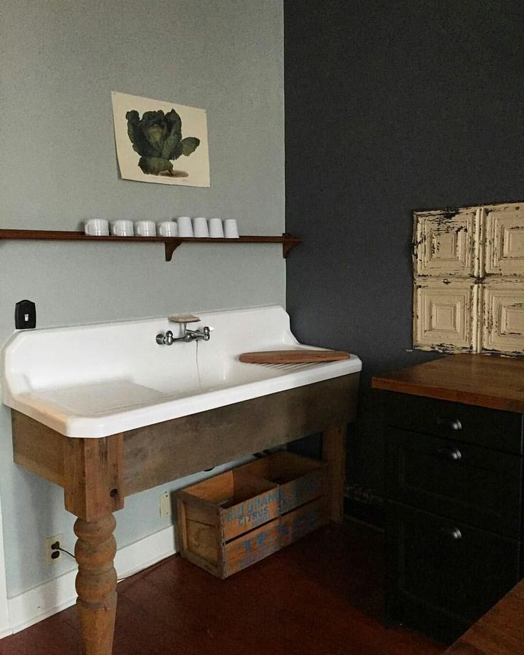 a white sink sitting on top of a wooden table next to a wall mounted painting