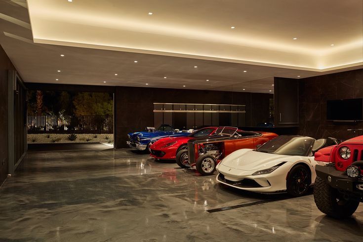 several different colored sports cars in a large room with lights on the ceiling and floor