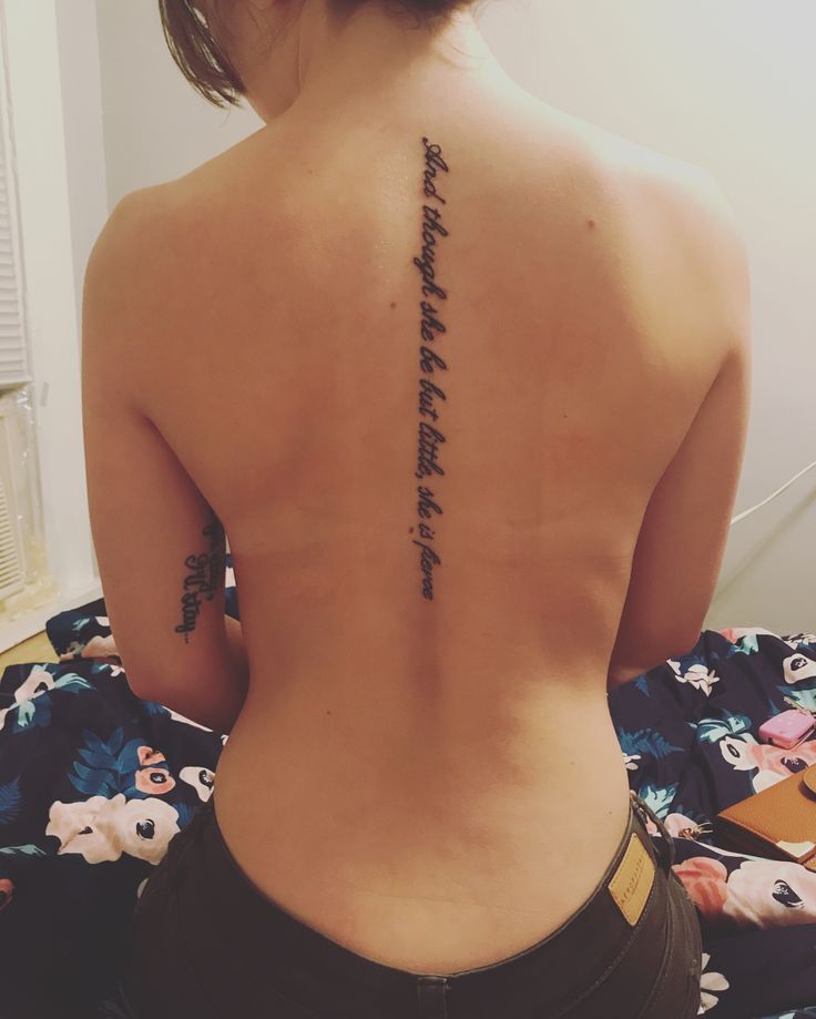 the back of a woman's upper body with writing on her left arm and lower back