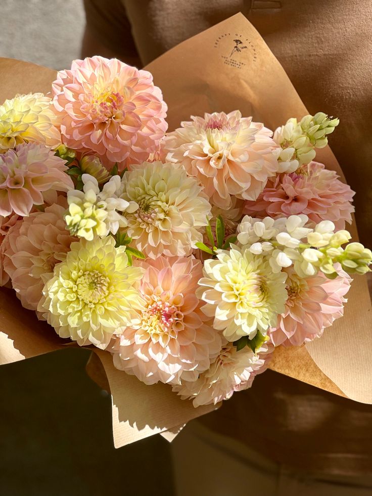 a person holding a bunch of flowers in their hands with paper wrapping around them and an envelope on the other side