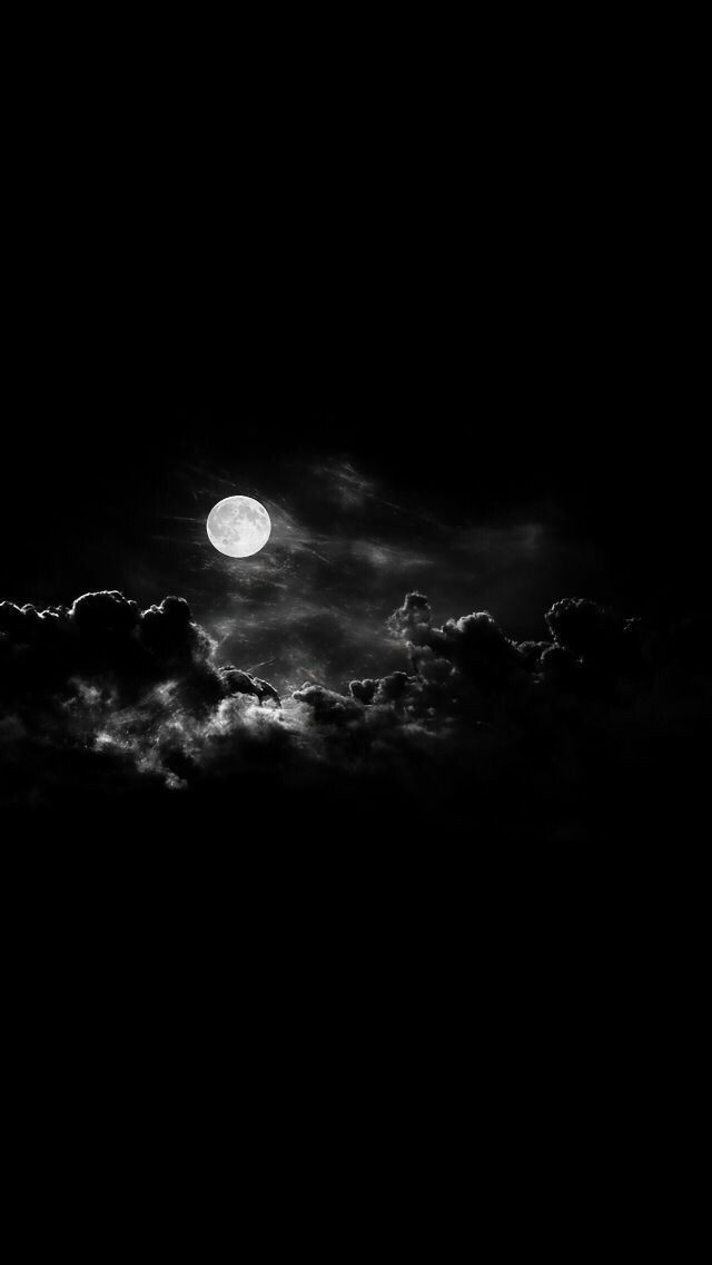 black and white photograph of the moon in the sky with clouds around it at night