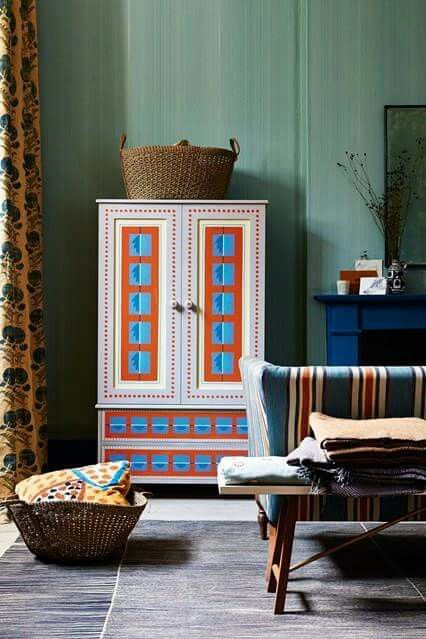 a living room filled with furniture next to a blue dresser and window covered in curtains