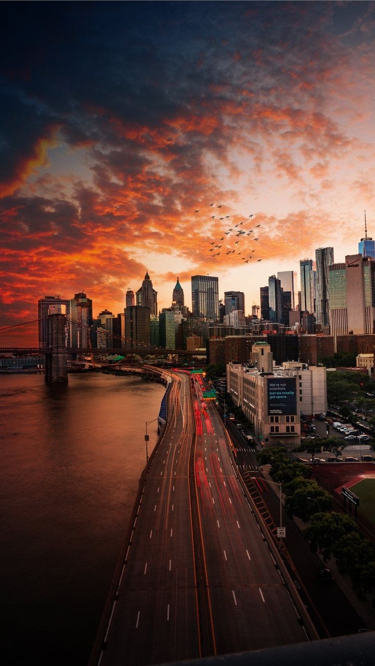 an aerial view of a city at sunset with the sun going down and cars driving on the road