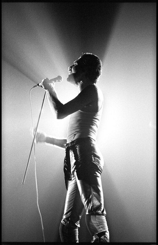 black and white photograph of a man singing into a microphone with his hands in the air