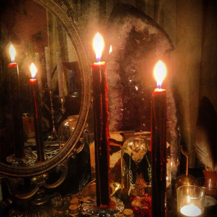 candles are lit in front of a mirror on a table with other items around it