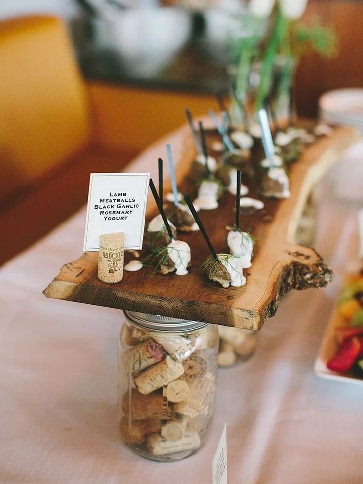 a wooden table topped with jars filled with small candies and marshmallows