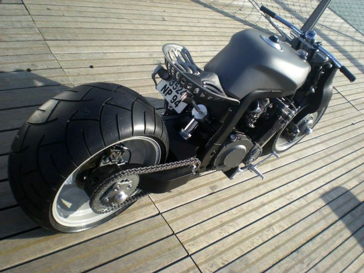 a black motorcycle parked on top of a wooden floor next to a fence and water