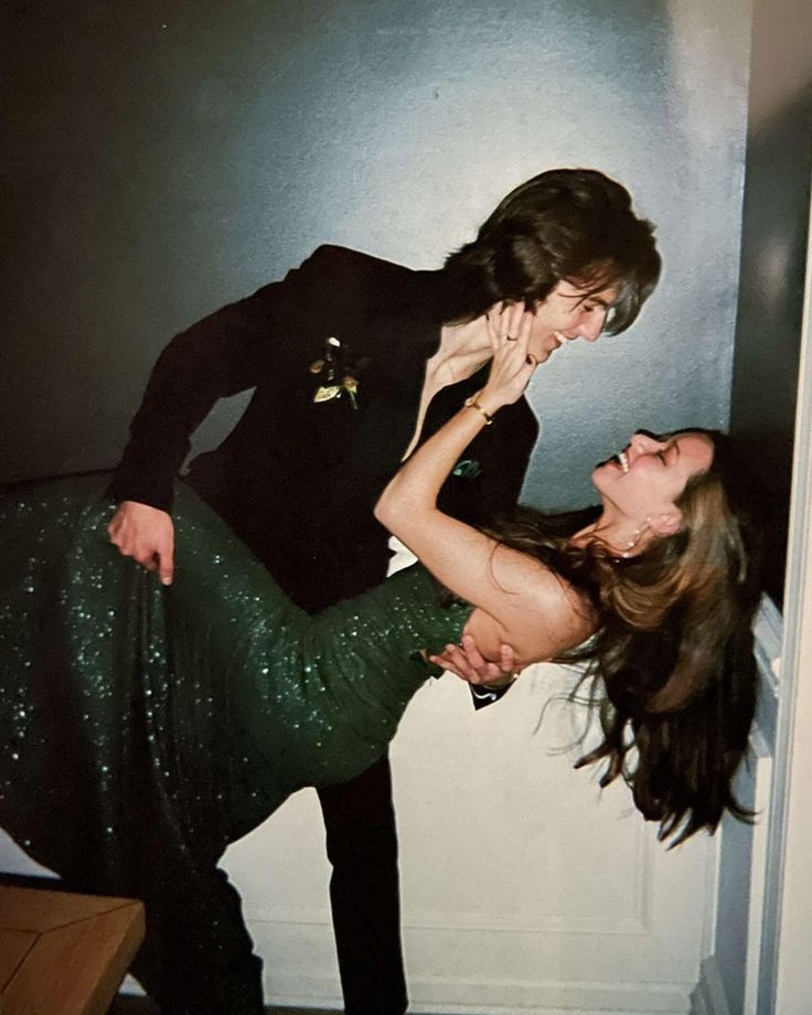 a man and woman are dancing together in the hallway, one is wearing a green sequin skirt