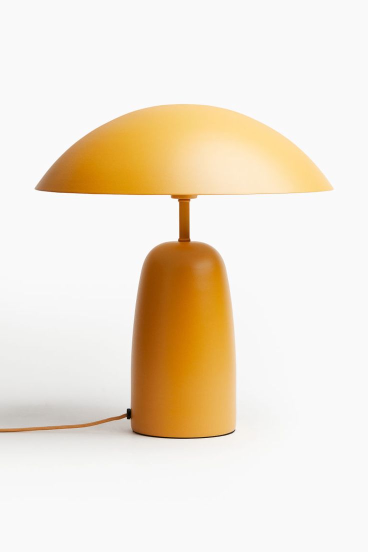 an orange table lamp sitting on top of a white floor next to a light bulb