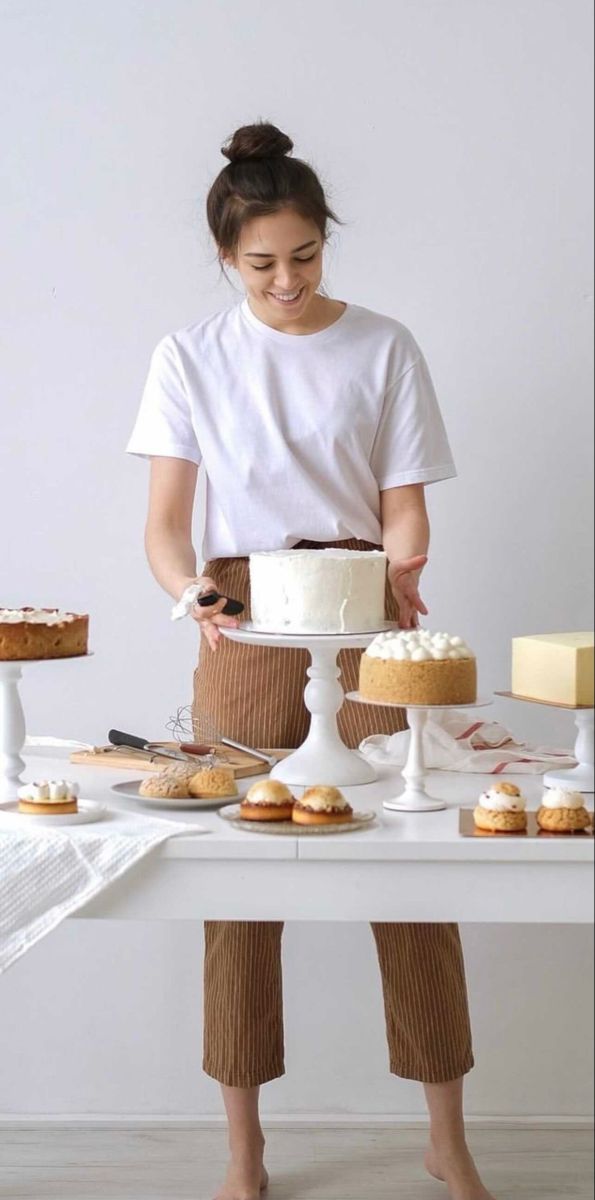 a woman standing in front of a table with cakes and desserts on top of it