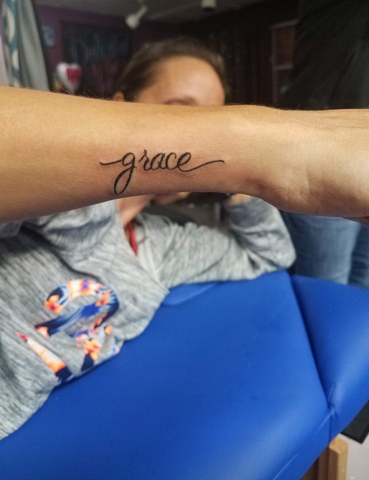 a woman with a tattoo on her arm that says grace in cursive writing