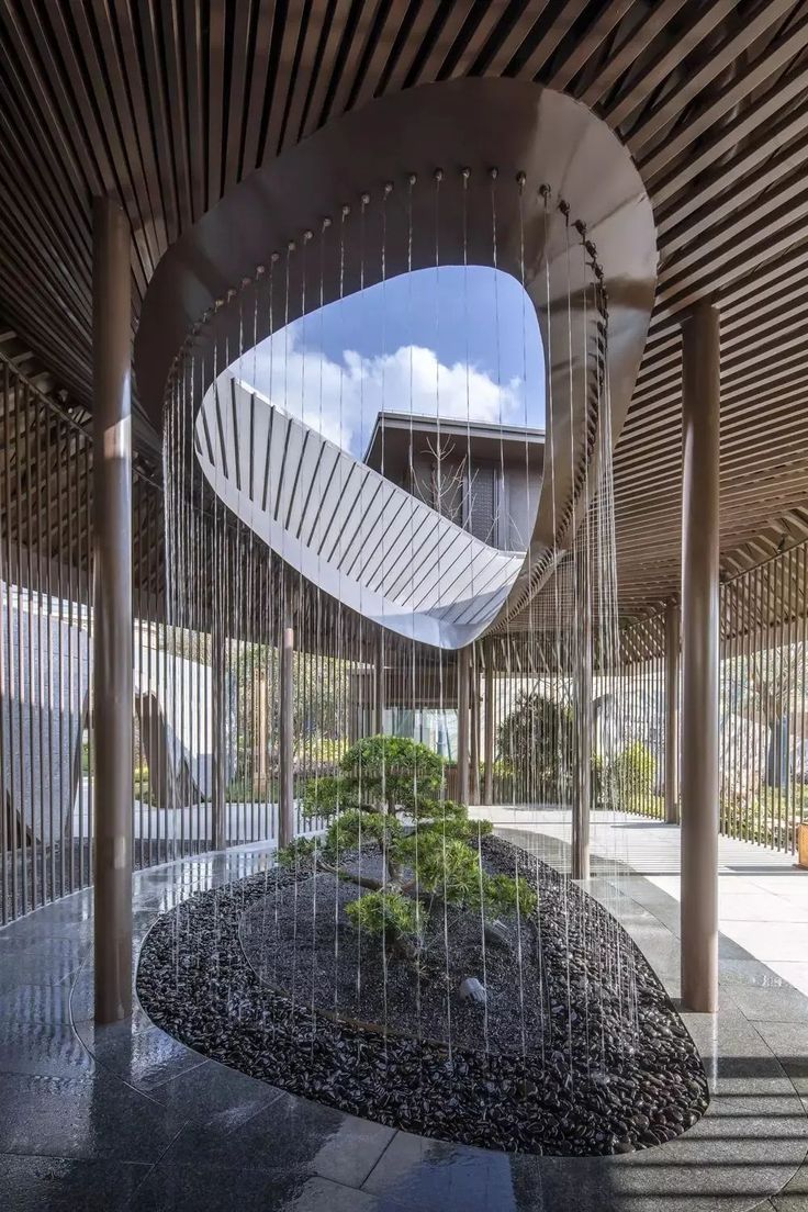 the inside of a building that has a circular fountain in front of it and plants growing out of the ground