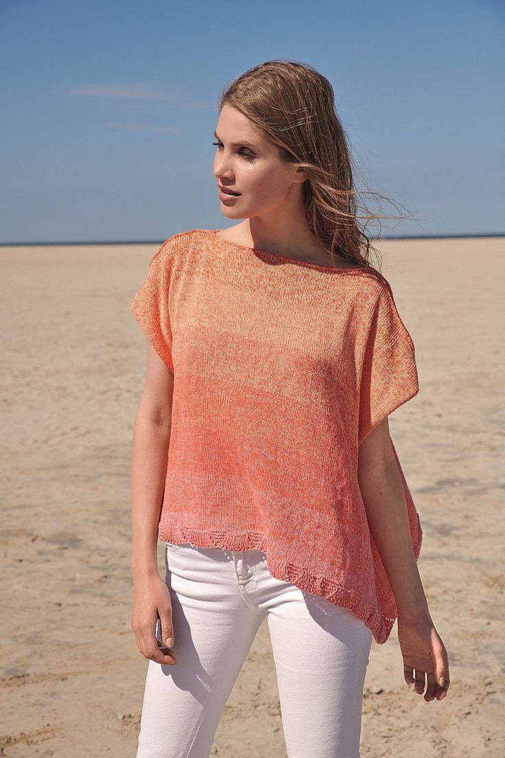 a woman standing on the beach wearing white pants and an orange top with short sleeves