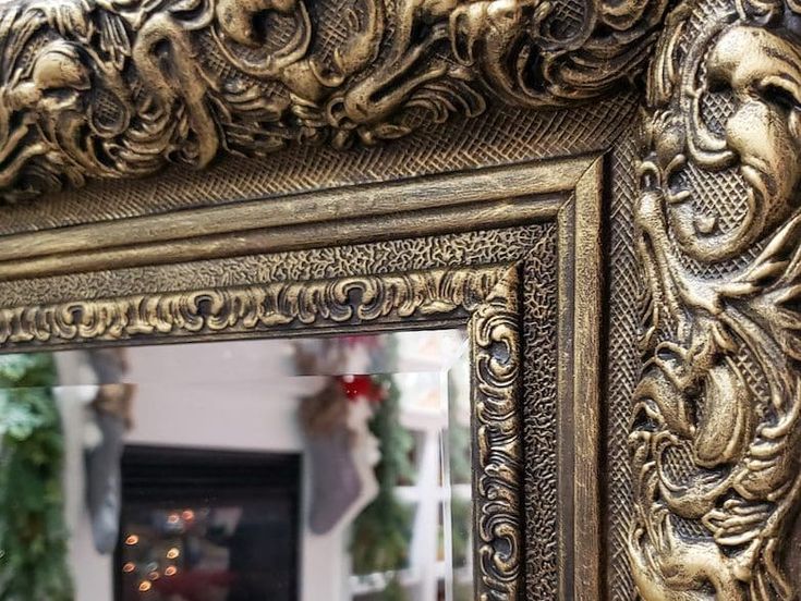 an ornate gold framed mirror in front of a fireplace