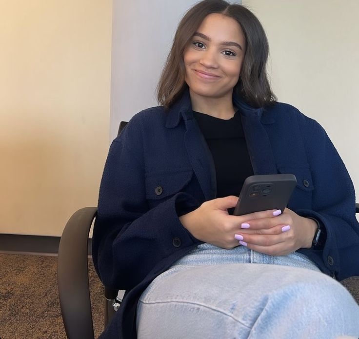 a woman sitting in a chair looking at her cell phone