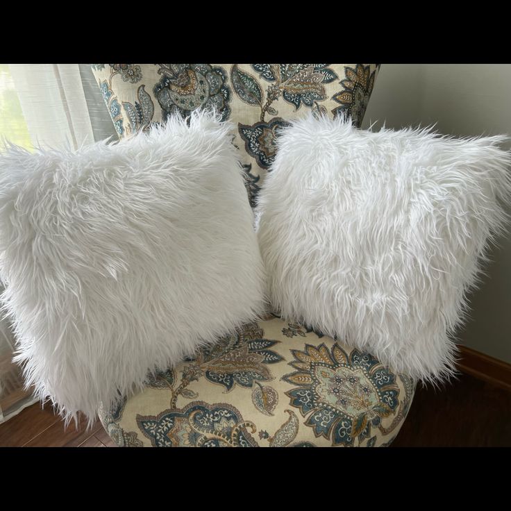 two white pillows sitting on top of a chair