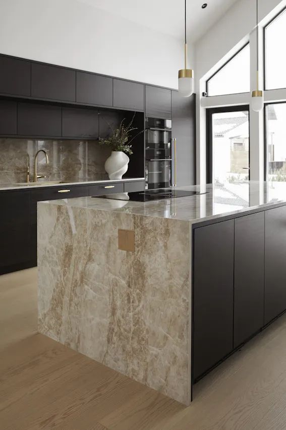 a modern kitchen with marble counter tops and black cabinets, along with an island in the middle