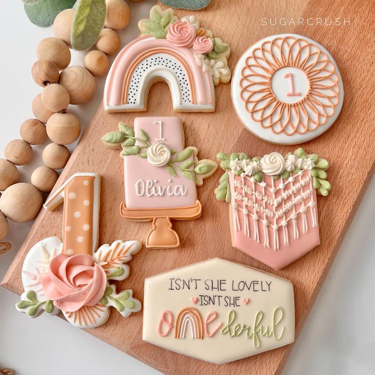 some cookies are on a wooden board and decorated with icing, flowers, and other decorations