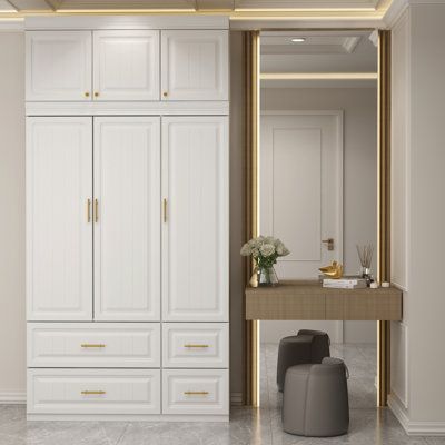 a dressing room with white cabinets and gold trim on the doors, along with a stool