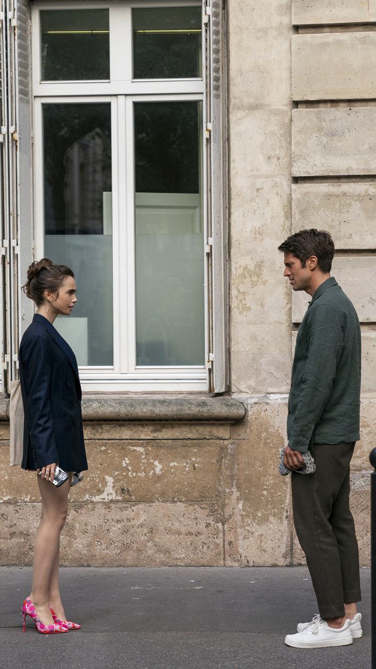 a man and woman standing in front of a window with their feet on the ground