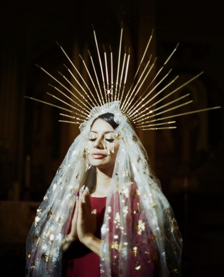 a woman in a red dress is wearing a white veil with gold stars on it