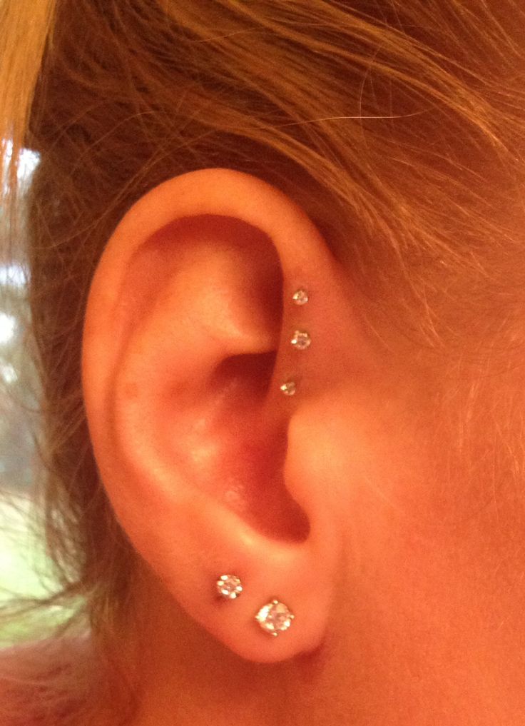 a close up of a person's ear with three piercings