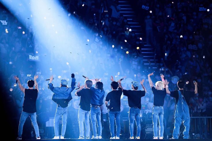 a group of men standing on top of a stage with their hands in the air