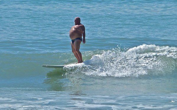 a man riding a surfboard on top of a wave in the ocean with his shirt off