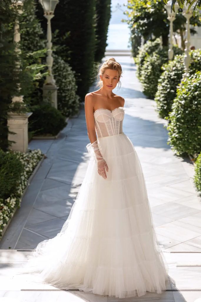 a woman in a wedding dress is walking down the street with her hand on her hip