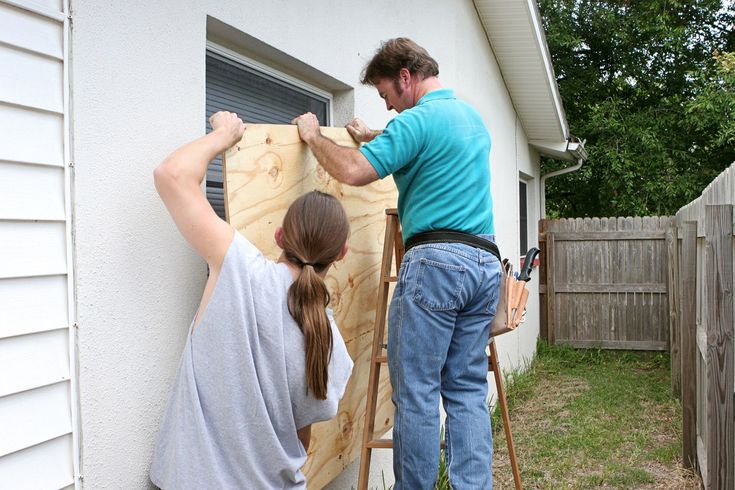 a man and woman are working on the siding of a house that's being built