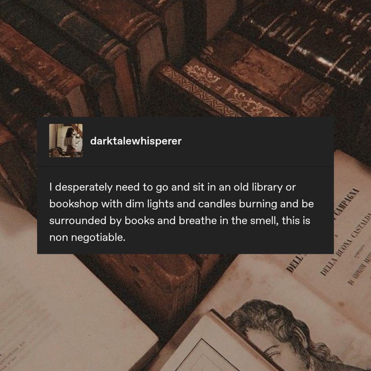 an open book sitting on top of a pile of books next to a stack of wooden boxes