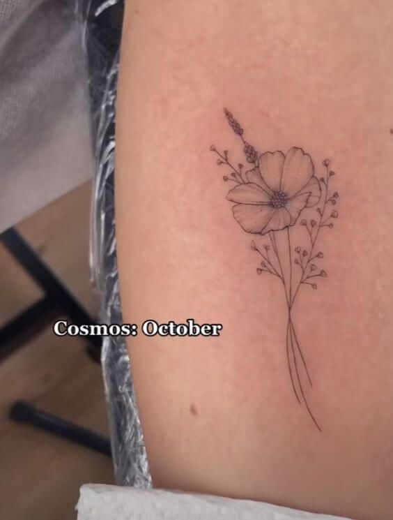 a small tattoo on the leg of a woman's thigh with flowers and leaves