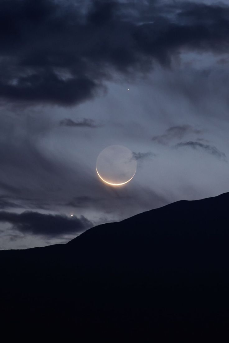 the moon and venus are seen through dark clouds