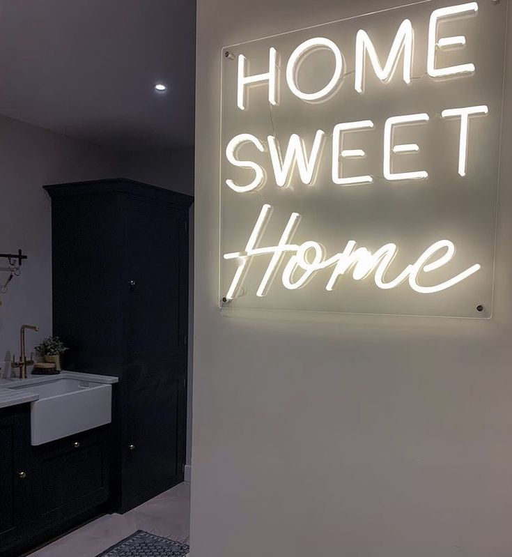 a neon sign that says home sweet home on the wall next to a bathroom sink